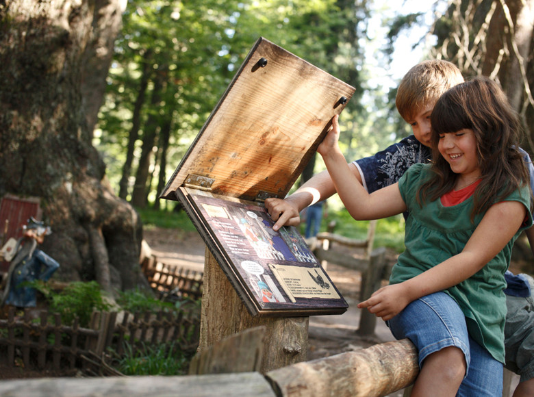 Sie klappt eine Holztafel auf und liest