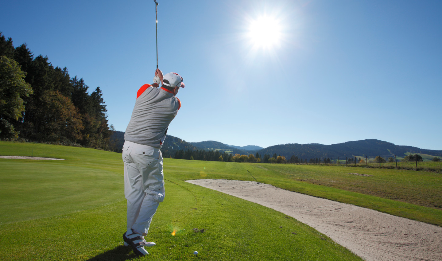 Mann spielt bei strahlendem Sonnenschein Golf