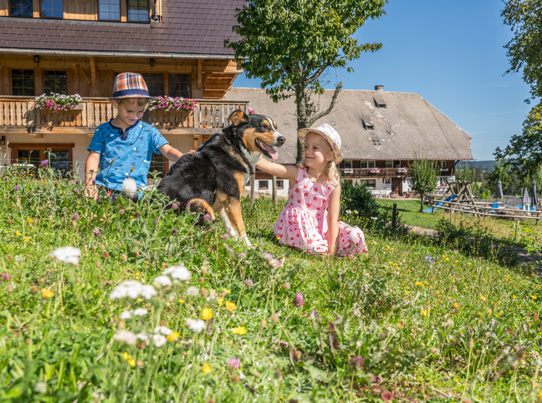 Kinder sitzen vor dem Haus und genießen die Zeit mit dem Hund