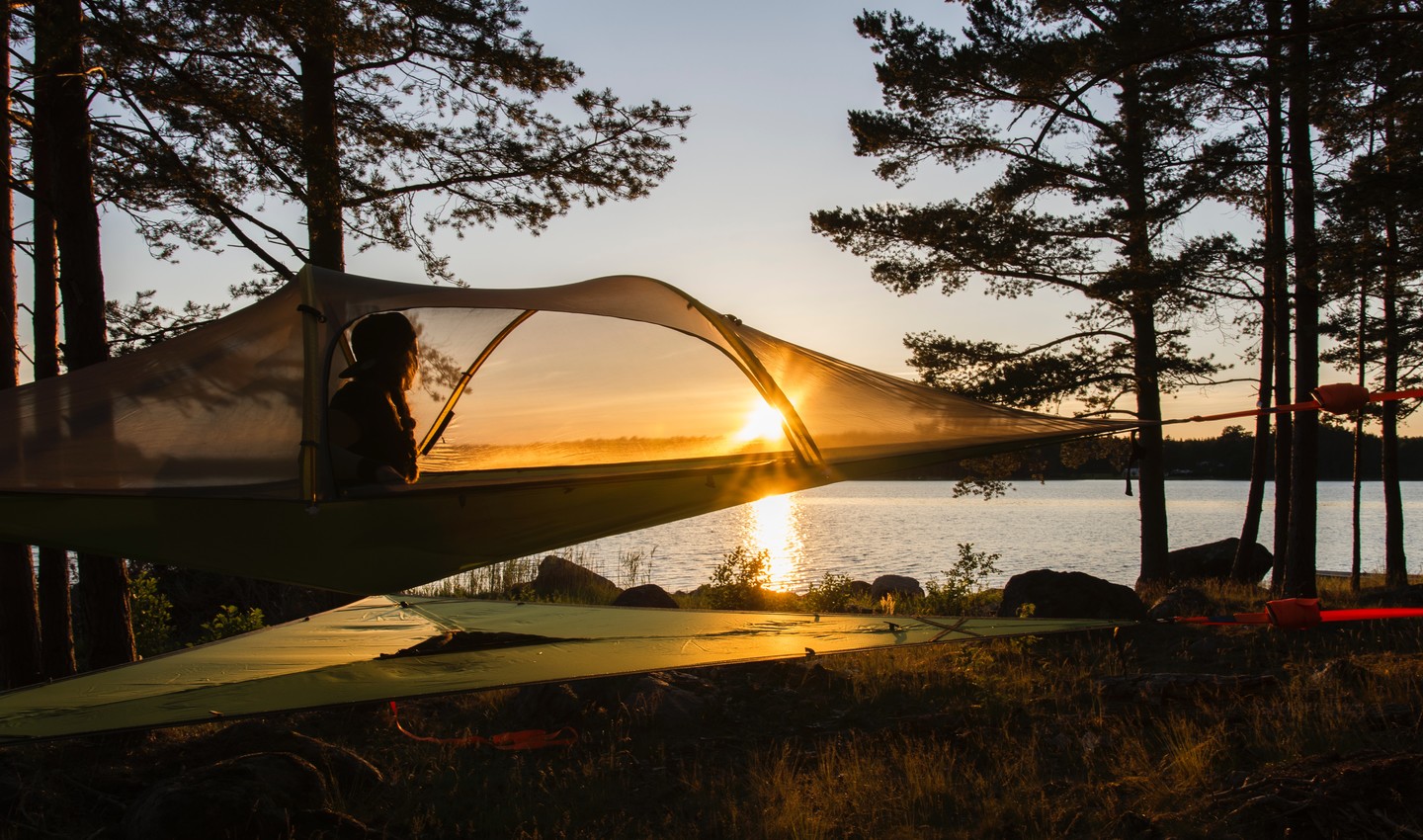 Person im Baumzelt bei Sonnenuntergang