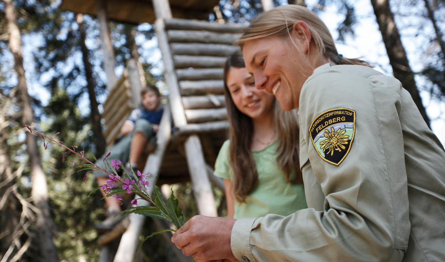 Rangerin erklärt Kinder etwas über Pflanzen