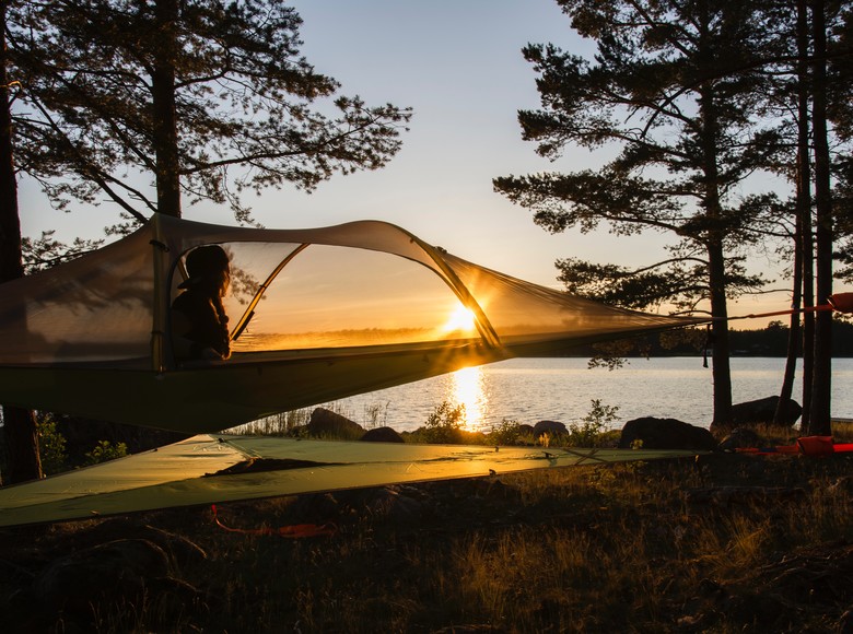 Person im Baumzelt bei Sonnenuntergang